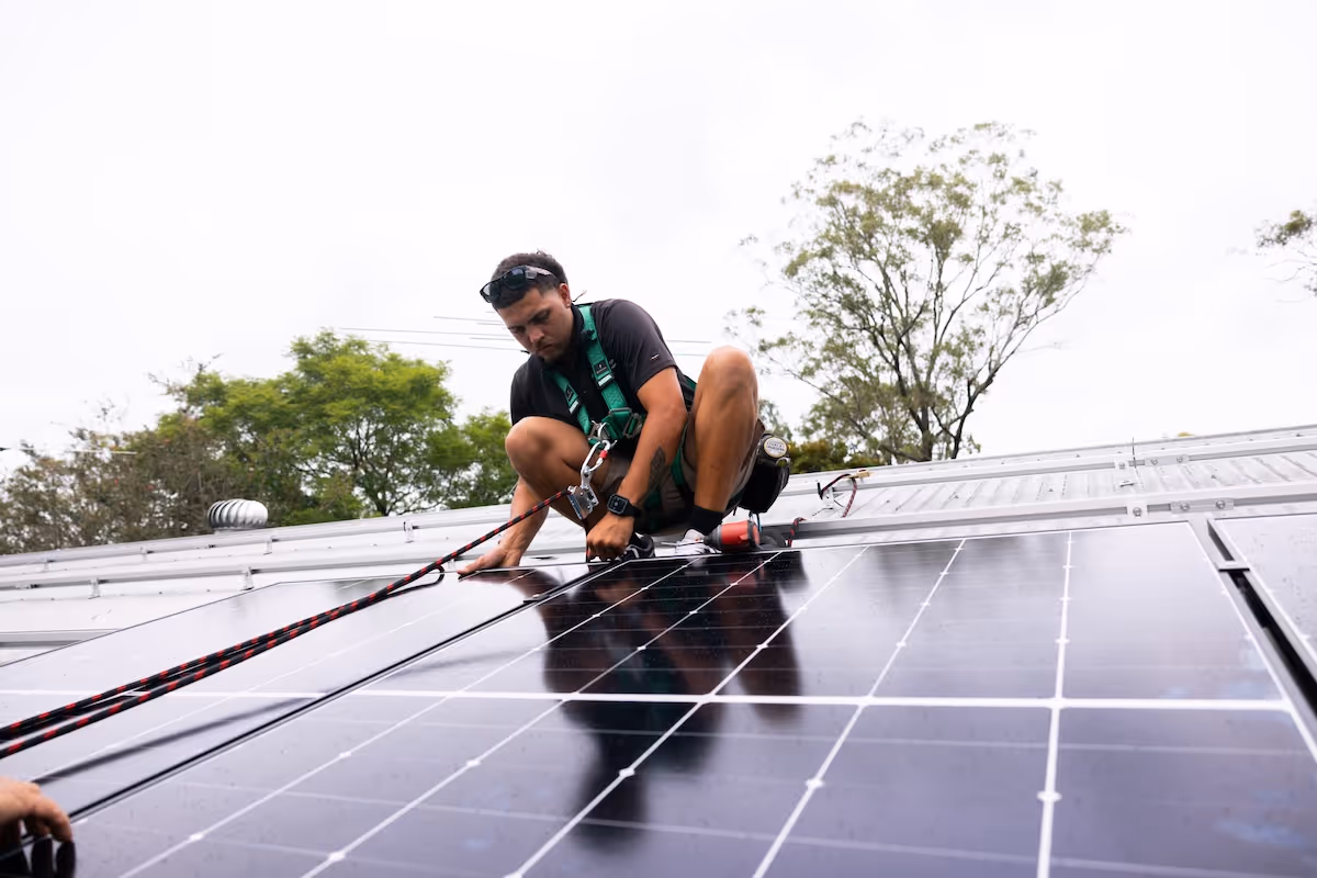 A qualified LMS electrician securing solar panels to a roof.