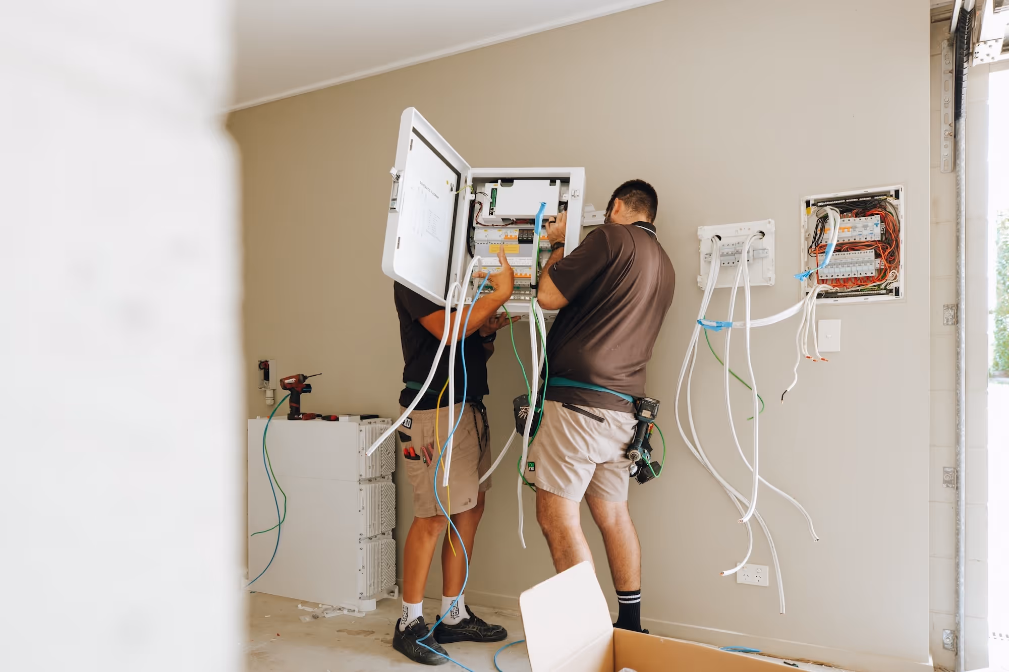 Two qualified LMS Electrical technicians performing complex wiring and installation of a smart energy system.